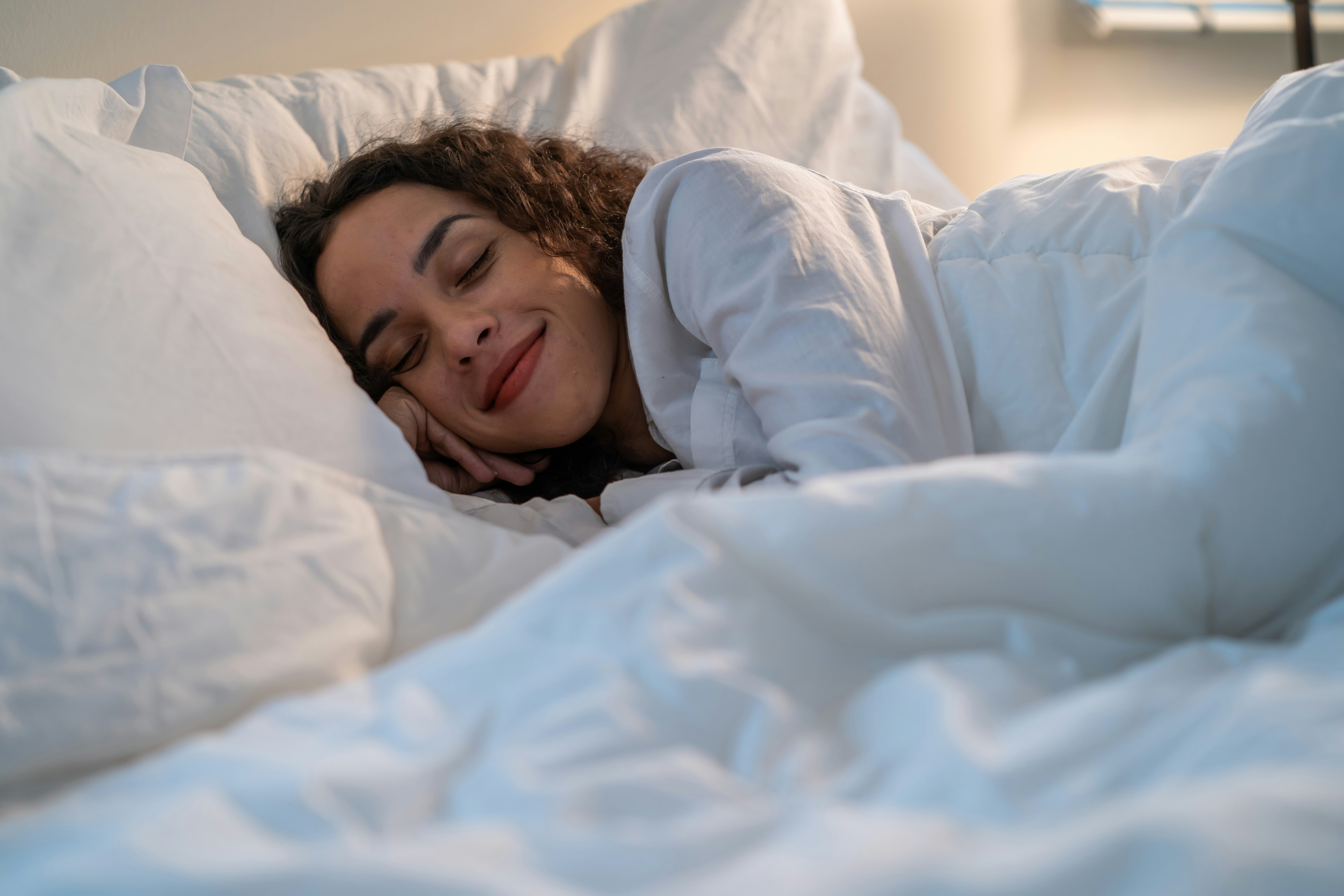 Woman sleeping peacefully under white bedding